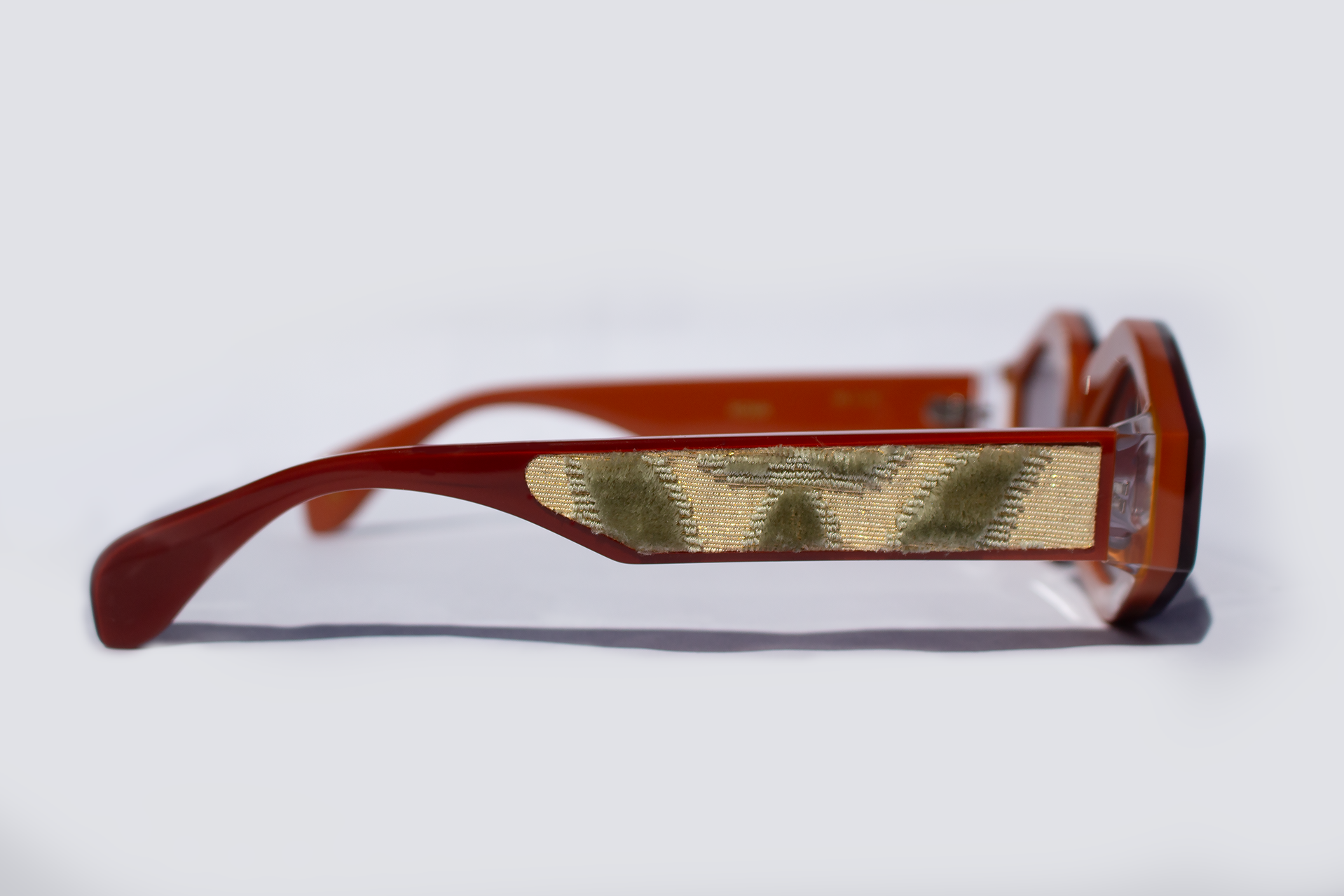 Dettaglio asta laterale occhiali da sole Roma, elegante, statement in acetato rosso e caco con inserto velluto fiorentino