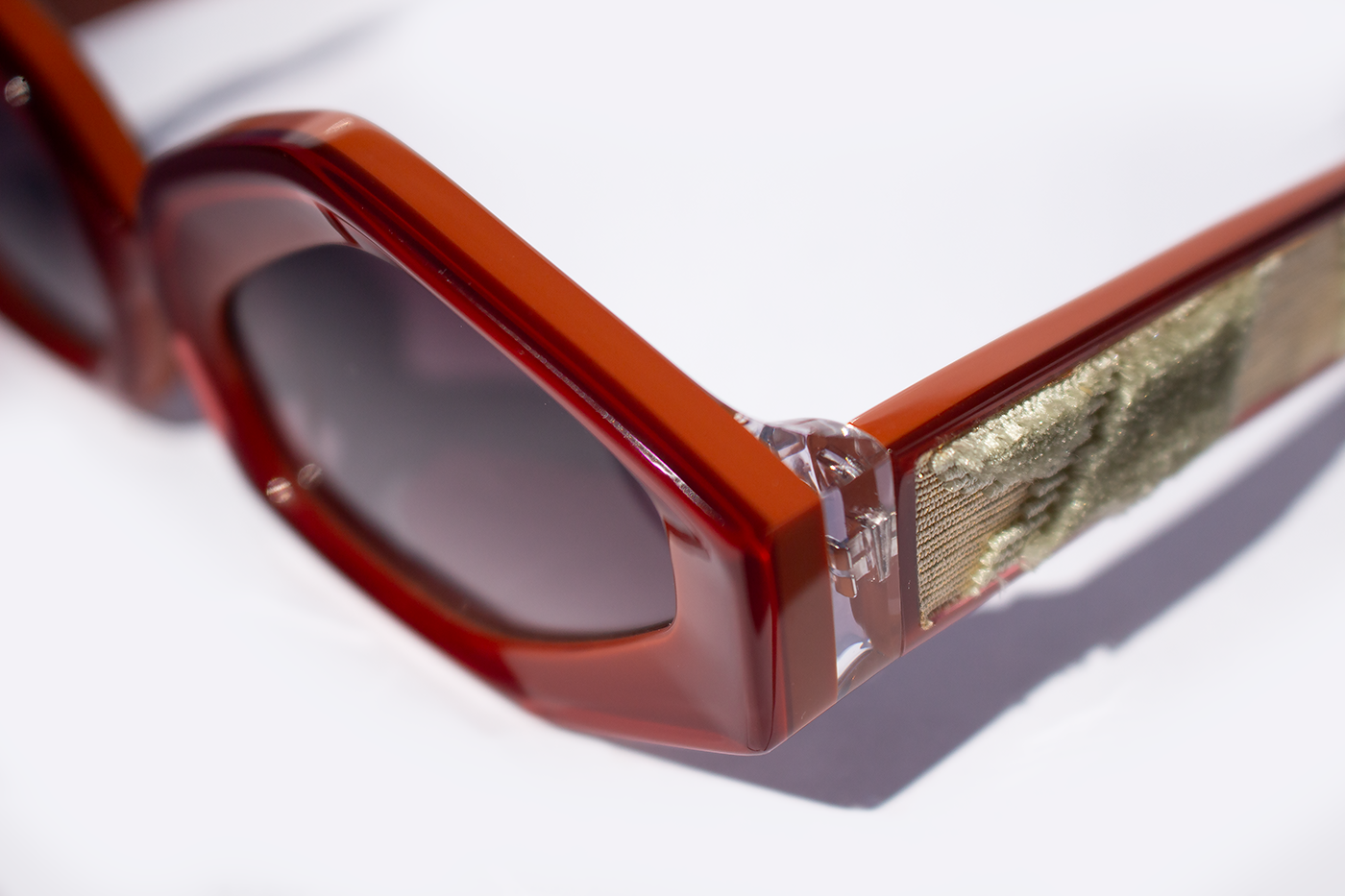 Dettaglio occhiali da sole Roma, elegante, statement in acetato rosso e caco con inserto velluto fiorentino